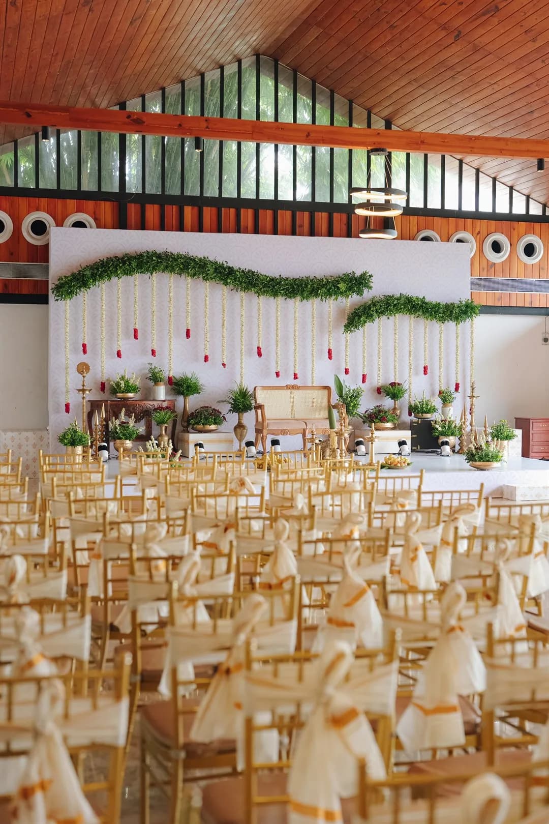 Garlanded ceremony stage with rows of draped gold chairs